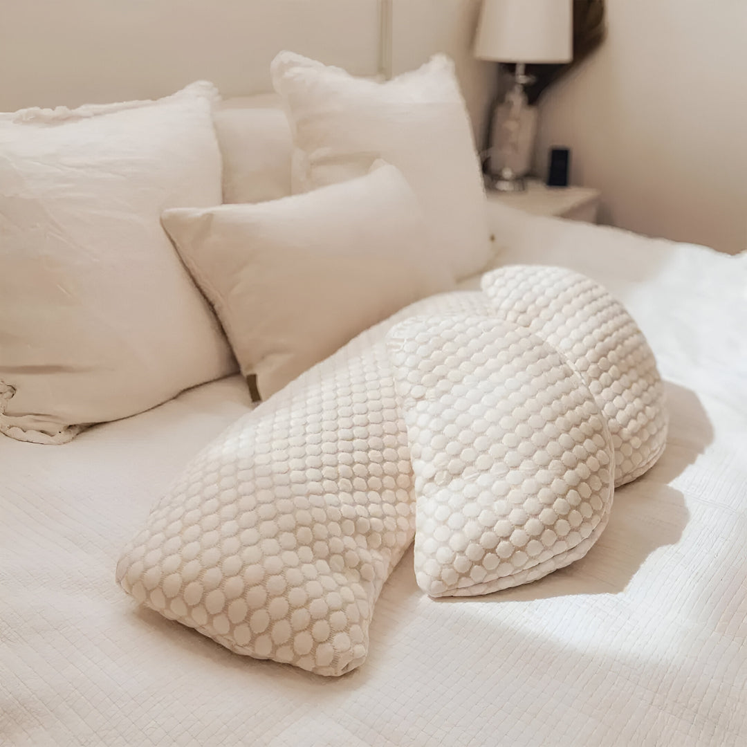 Coussin de grossesse blanc posé sur un lit, offrant confort et soutien pour les futures mamans.
